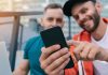 Two smiling men use an app