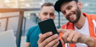Two smiling men use an app