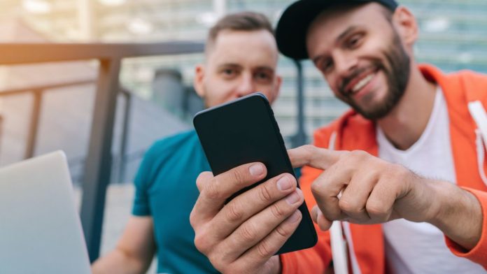 If-sportsbooks-want-satisfied-players,-they'd-better-work-on-their-app Two smiling men use an app