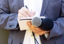 Hand with notebook holding microphone