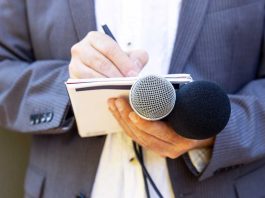 Hand with notebook holding microphone