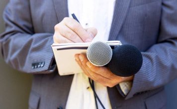 Hand with notebook holding microphone