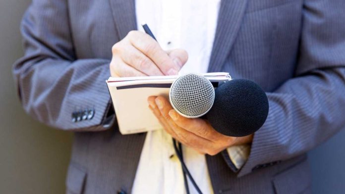 Hand with notebook holding microphone