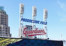 A Cleveland Guardians sign and floodlights at Progressive Field