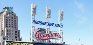 A Cleveland Guardians sign and floodlights at Progressive Field