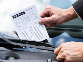 A person putting a violation notice on a car windshield