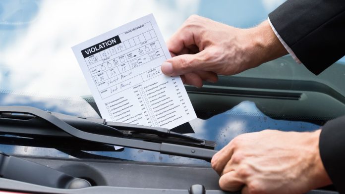 Tennessee-fines-5-offshore-sportsbooks-in-quest-to-'eliminate'-bad-actors A person putting a violation notice on a car windshield