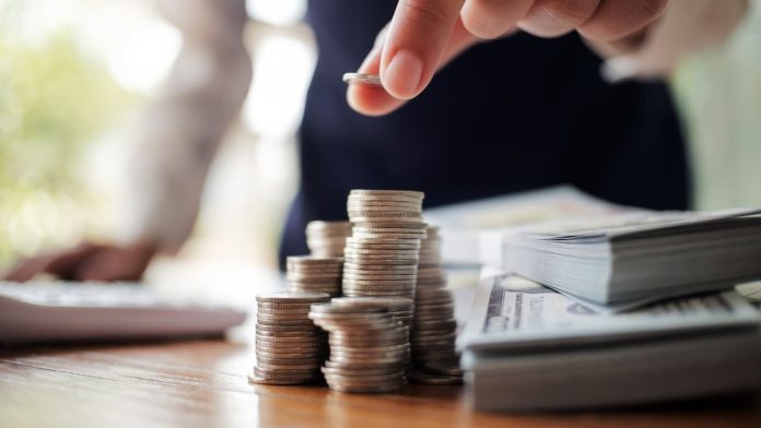 VGW-now-charges-customers-sales-tax-when-they-buy-Gold-Coins A person stacking dollar bills and counting coins