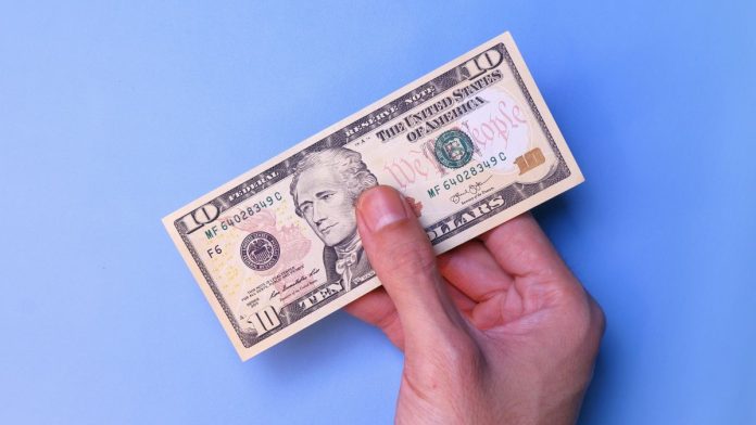 A person's hand holding an American $10 bill