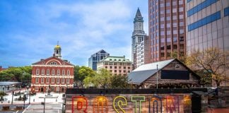 A Boston sign with Boston architecture in the background