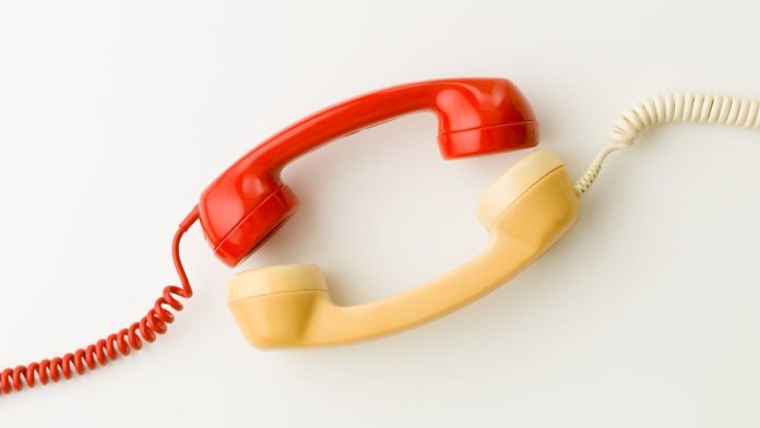 Two wired telephone receivers facing each other
