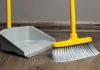 A broom sweeping a floor into a dustpan