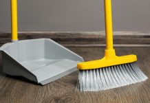 A broom sweeping a floor into a dustpan