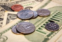 U.S. coins including quarters lying on $1 and $5 notes