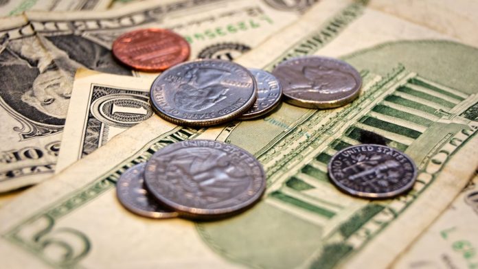 U.S. coins including quarters lying on $1 and $5 notes