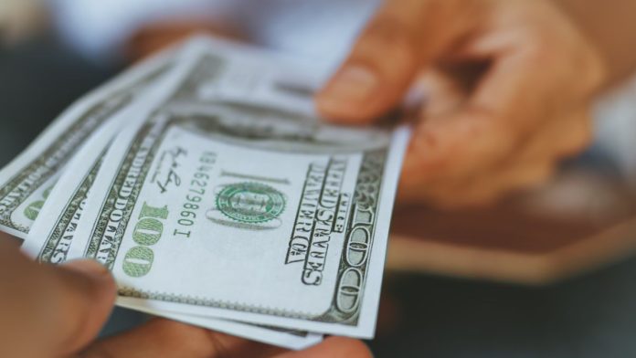 Illinois-sportsbooks-paid-$5.2M-in-extra-tax-in-first-month-of-per-wager-fee A person handing over money, as if to the taxman