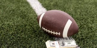 Kalshi trading volume soars far above $400M in NFL Week 1 An NFL football lying on a football field next to a stack of U.S. banknotes