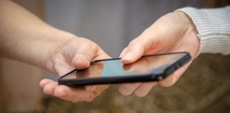 NJ court orders NCPG to cease using 1-800-GAMBLER helpline A person handing over a phone to another person