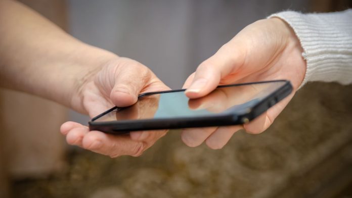 NJ-Superior-Court-orders-NCPG-to-hand-over-1-800-GAMBLER A person handing over a phone to another person