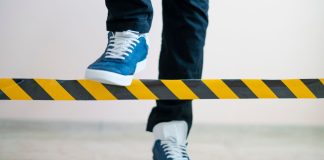 A person stepping over a barrier intended to limit their movement