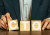 A person holding wooden blocks spelling out CTO, short for Chief Technology Officer
