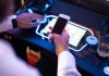 Live slot streaming company Awager acquired by Aristocrat Man has phone at slot machine as Aristocrat acquires live slot streaming company Awager.