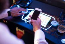 Live slot streaming company Awager acquired by Aristocrat Man has phone at slot machine as Aristocrat acquires live slot streaming company Awager.