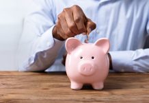 A person paying a coin into a piggy bank
