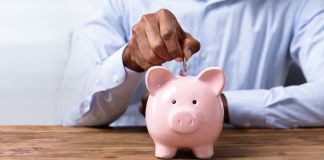 FanDuel and DraftKings pay the price in Illinois in August A person paying a coin into a piggy bank
