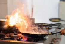 A person burning off a frying ban on a stovetop