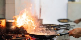 A person burning off a frying ban on a stovetop