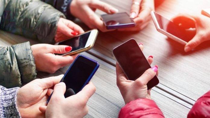 People with their phones being social as PrizePicks debuts a new social feature.