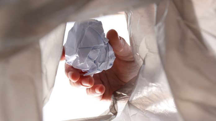 FanDuel-&-DraftKings-throw-out-Nevada-license-applications A person throwing crumpled up paper into a garbage bag