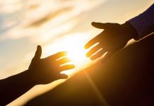 Two people's arms reaching out to each other for help