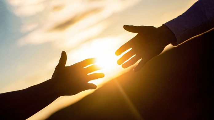 Genius-Sports-says-prediction-markets-may-need-its-help Two people's arms reaching out to each other for help