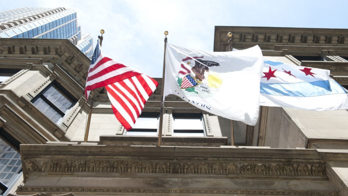 The flags of the USA, the state of Illinois and the city of Chicago flying from a building