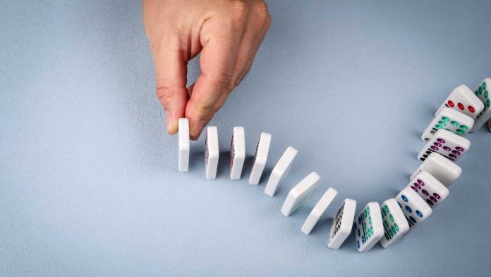 Hand stopping dominos from falling
