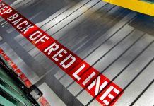 A sign on the floor warning people to stay behind the red line