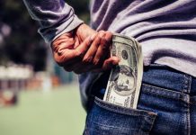 A person putting U.S. banknotes in his back pocket
