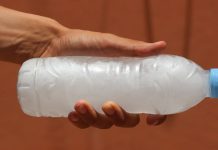 A person holding a water bottle full of frozen water turned to ice
