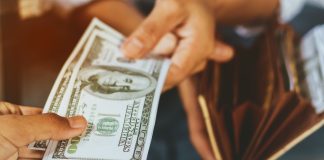 Person taking money out their wallet as DraftKings is required to handle payouts.