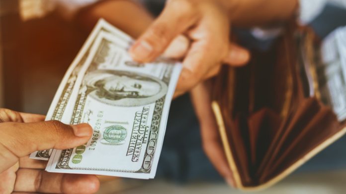 Person taking money out their wallet as DraftKings is required to handle payouts.
