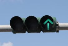 An overhead traffic light showing a green arrow to proceed