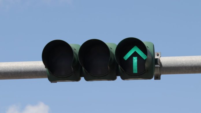 An overhead traffic light showing a green arrow to proceed