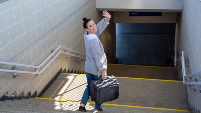 Fanatics-no-longer-an-American-Gaming-Association-member A woman waving goodbye over her shoulder as she heads to catch a subway train with a suitcase