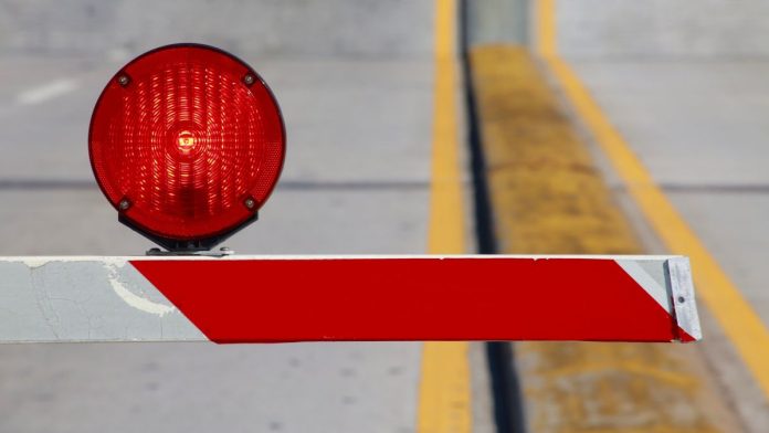 A barrier keeping people out of a certain area, with a red warning light