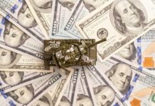 Toy tank sitting on a pile of hundred dollar bills