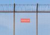 A barbed wire fence with a restricted sign on it
