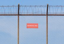 A barbed wire fence with a restricted sign on it
