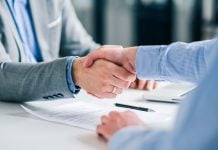 PENN extends retail sportsbook deal with Kambi Two businesspeople shaking hands with a pen and paper on the desk